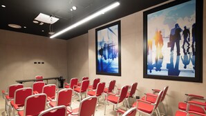 Un salón de conferencias con sillas rojas y una pantalla para proyector.