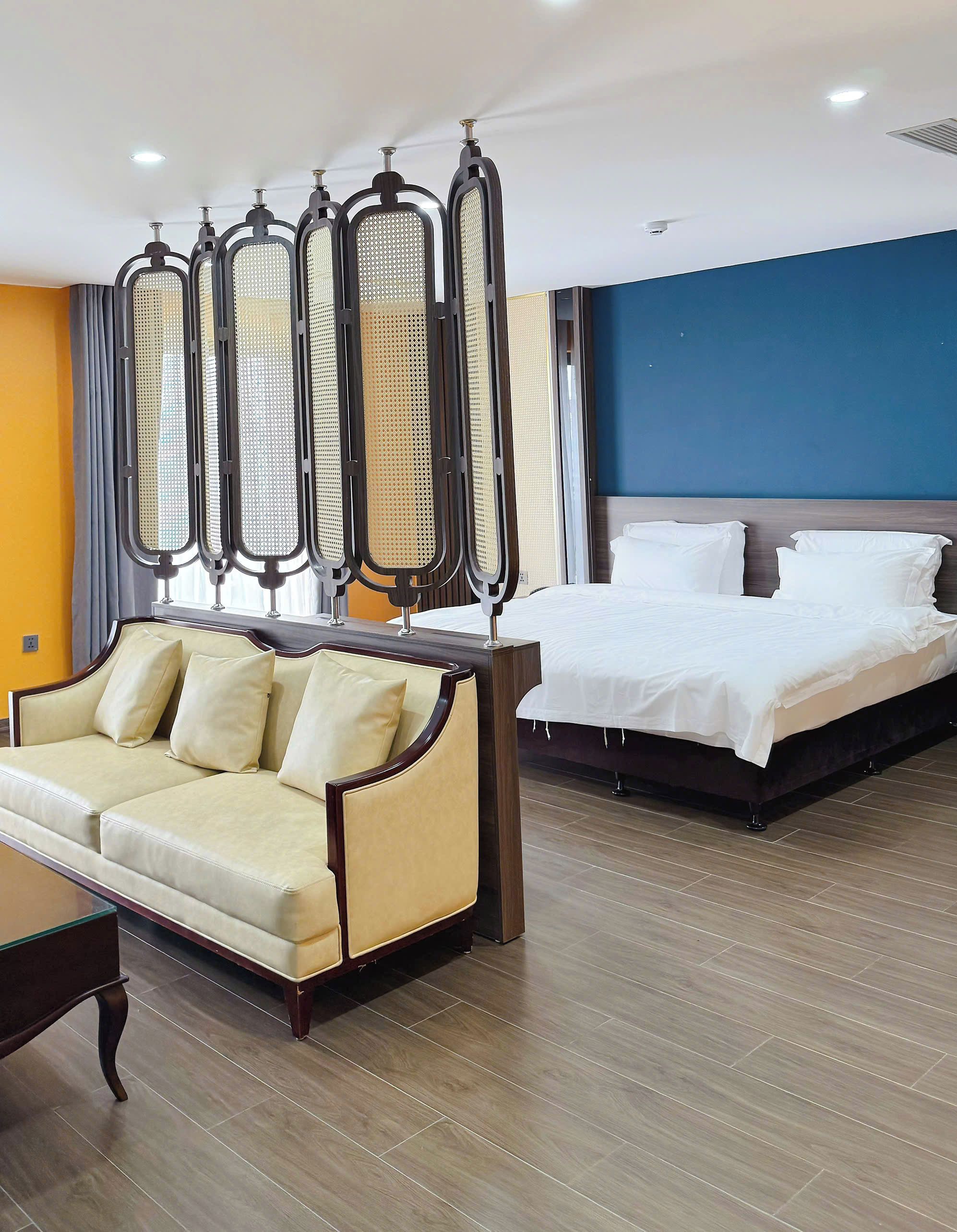 A hotel room with a bed, a sofa, and a large window.