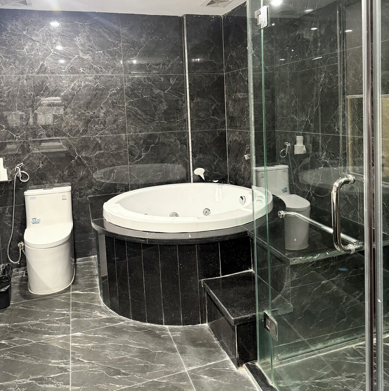 A modern bathroom with a freestanding bathtub, a glass-enclosed shower, and a toilet.