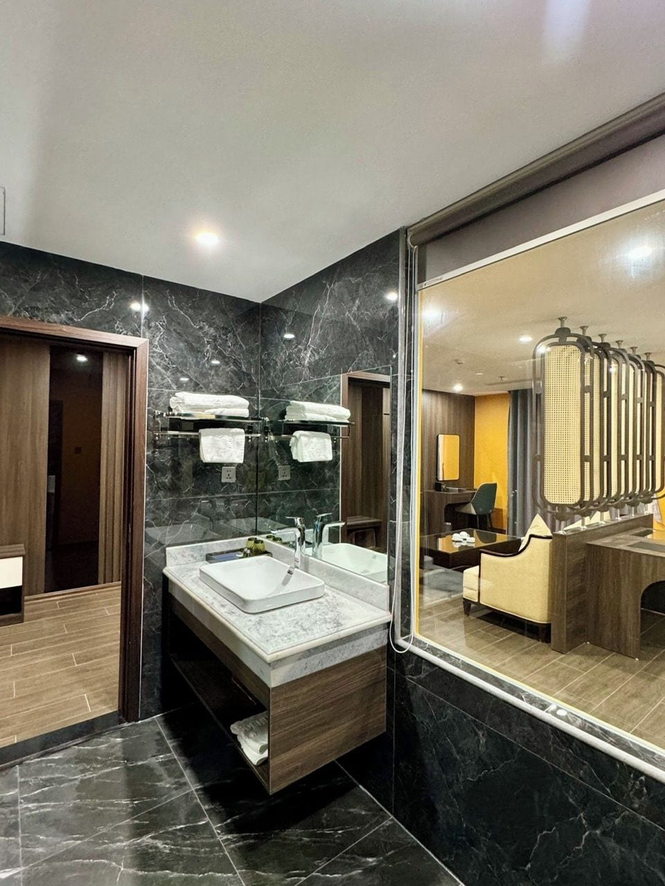A modern bathroom with a marble vanity, a large mirror, and a glass-enclosed shower area.