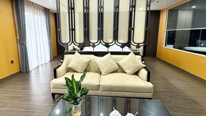 Ein modernes Wohnzimmer mit einem beigen Sofa, einem Glastisch und einer Zierpflanze.