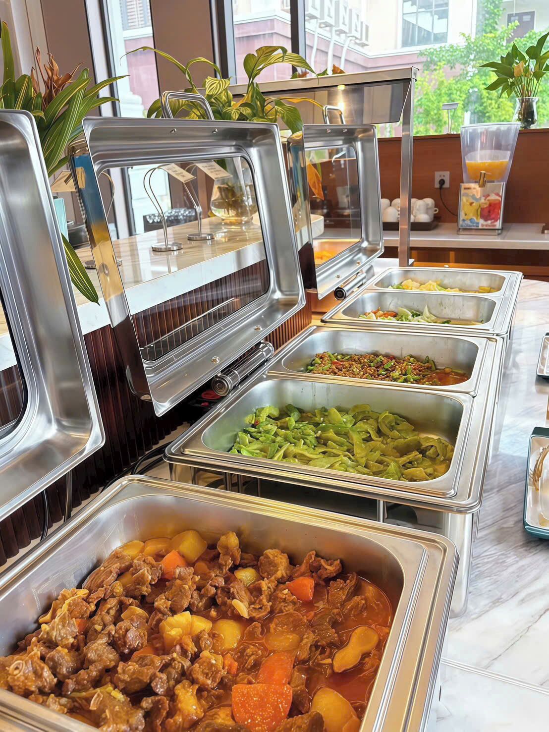 Un bufé con diversas opciones de comida, incluyendo platos de carne, ensaladas y una bebida de frutas.