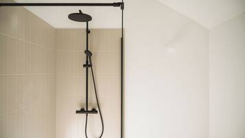 A shower with a handheld showerhead and a handheld scrubber.
