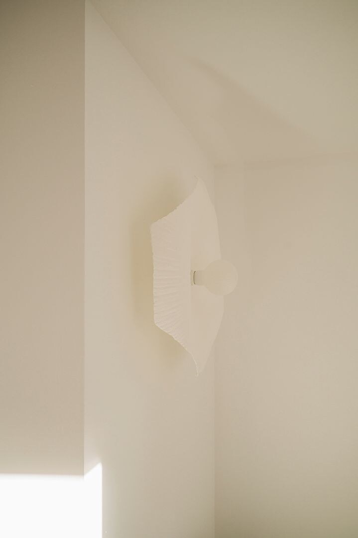 A room with a plain white wall and a single light fixture.