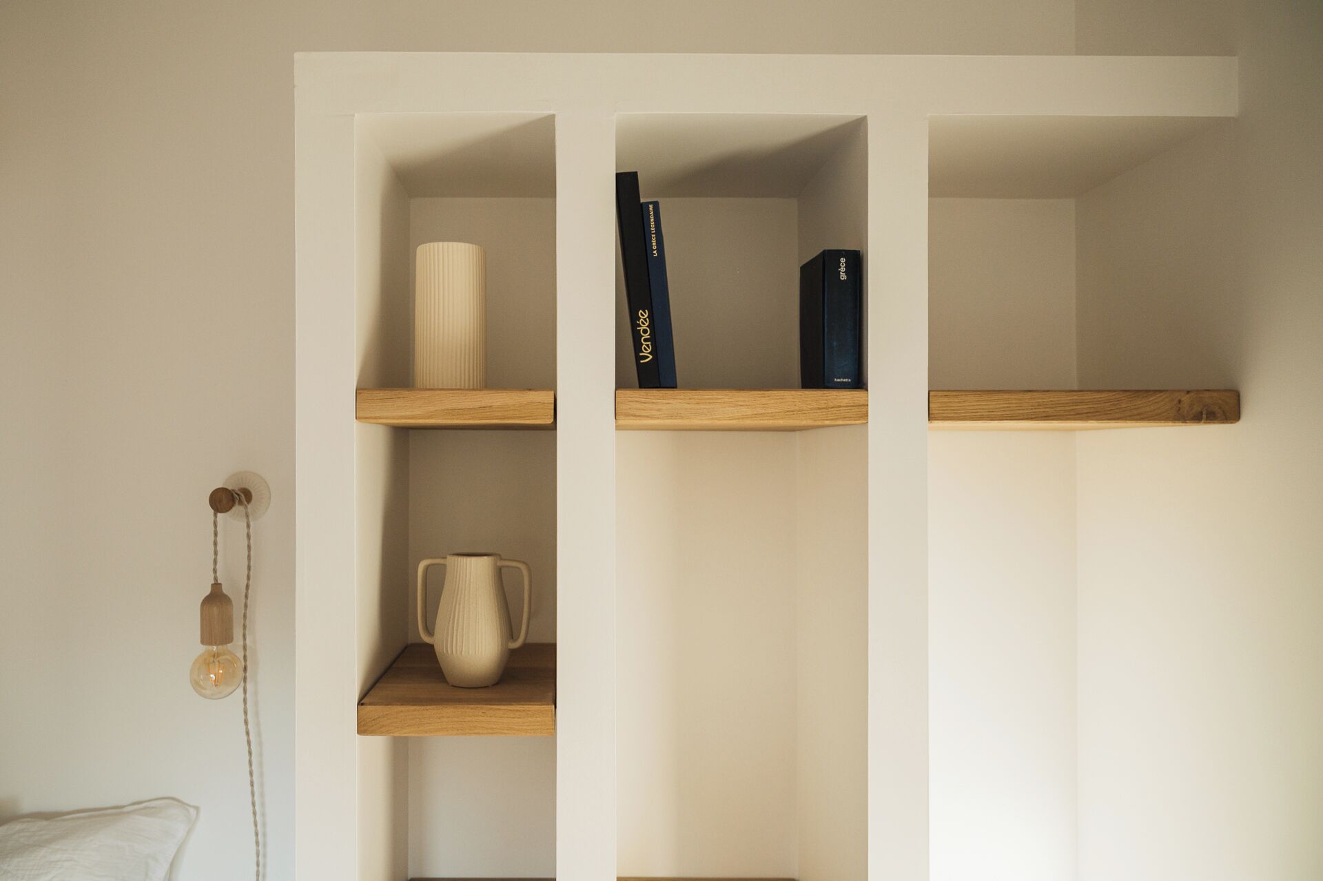 Une étagère minimaliste avec des livres et un vase.