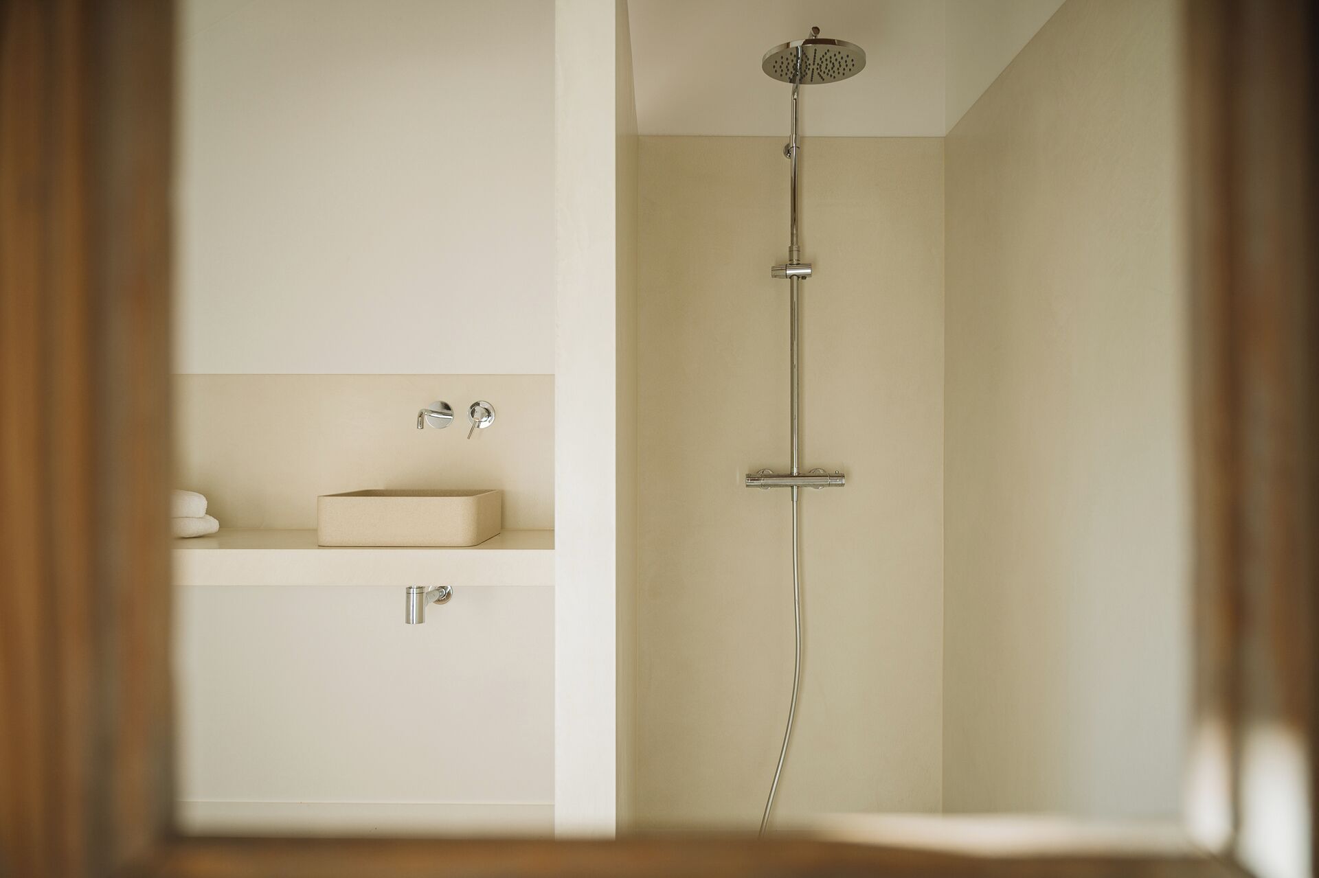 A minimalist bathroom with a shower, a sink, and a towel rack.