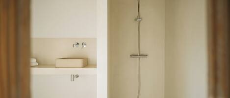 A minimalist bathroom with a shower, a sink, and a towel rack.