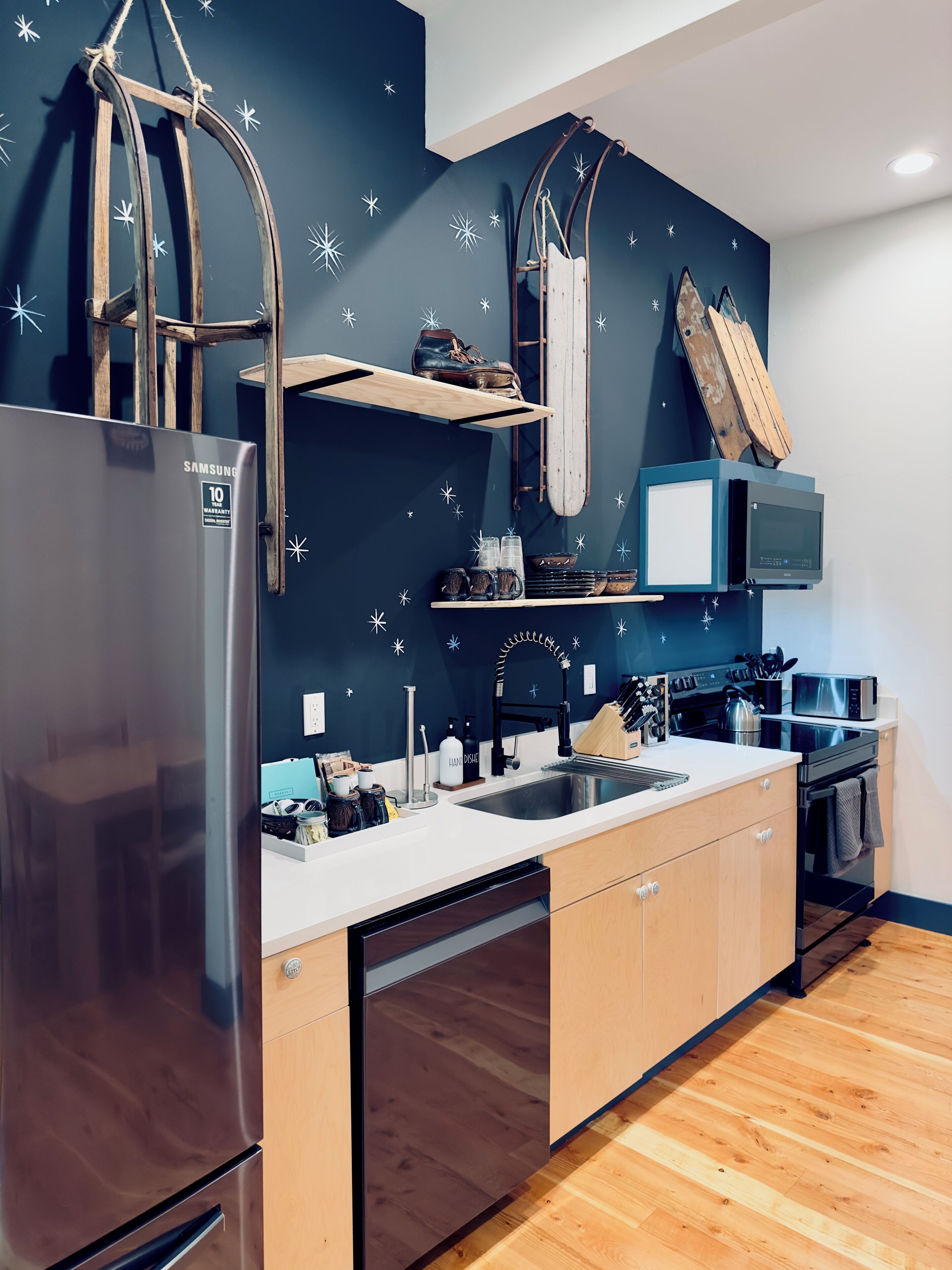 A modern kitchen with a stainless steel refrigerator, wooden cabinets, a double sink, and a microwave.