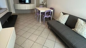 Un espacio habitable compacto con comedor, sofá y televisor.