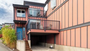 Un immeuble résidentiel à plusieurs étages, doté d’un balcon, d’une porte bleue et d’un escalier apparent menant à l’entrée.