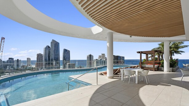 A rooftop pool area with a city view, lounge chairs, and a wooden pergola. - Modern 2 Bedroom Apartment in Broadbeach - Q Stay (Gallery 206 - 2N - NB) (Broadbeach)