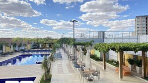 Zona de piscina en la azotea con vistas despejadas al cielo, rodeada de mobiliario exterior y vegetación.