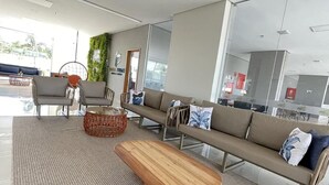 Un área de estar moderna con sofá, sillones, una mesita de centro y un separador de vidrio.