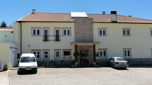 Un bâtiment à deux étages, doté d’un toit en tuiles, d’une entrée centrale et d’un espace de stationnement pouvant accueillir deux voitures.