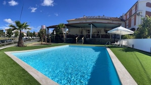 Une piscine rectangulaire à l’eau d’un bleu limpide, entourée d’une pelouse artificielle verdoyante.