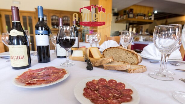 Une table dressée avec des bouteilles de vin, des verres, du pain et de la charcuterie.