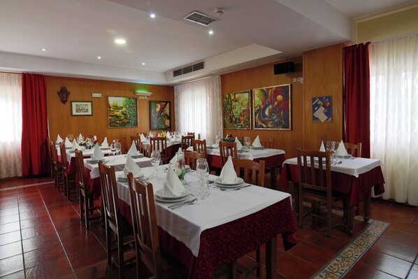 A dining area with multiple tables set for service, wooden walls, and artwork on the walls. - Hotel A vileira (Vimioso)