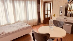A room with a bed, a round dining table with chairs, a dresser, and a mirror. - Fazilet Hanım Konağı (Gaziantep)