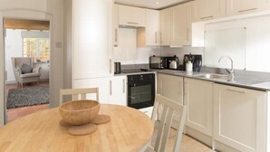 Una cocina moderna con armarios blancos, una mesa de comedor de madera y un horno negro.