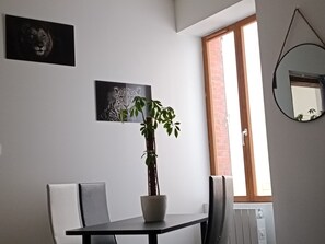 Enjoy meals in this stylish dining area with a dining table, two chairs, and a potted plant.
