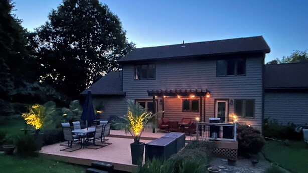 A two-story house with a patio area featuring outdoor furniture and a small pool.