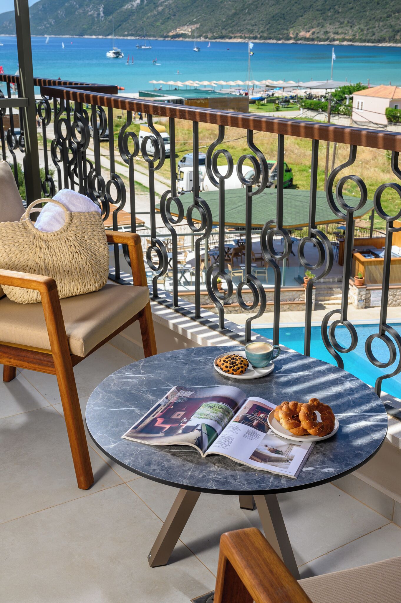 Ein Balkon mit Blick auf das Meer, ein runder Tisch mit einer Zeitschrift, einer Tasse und einem Teller Kekse.