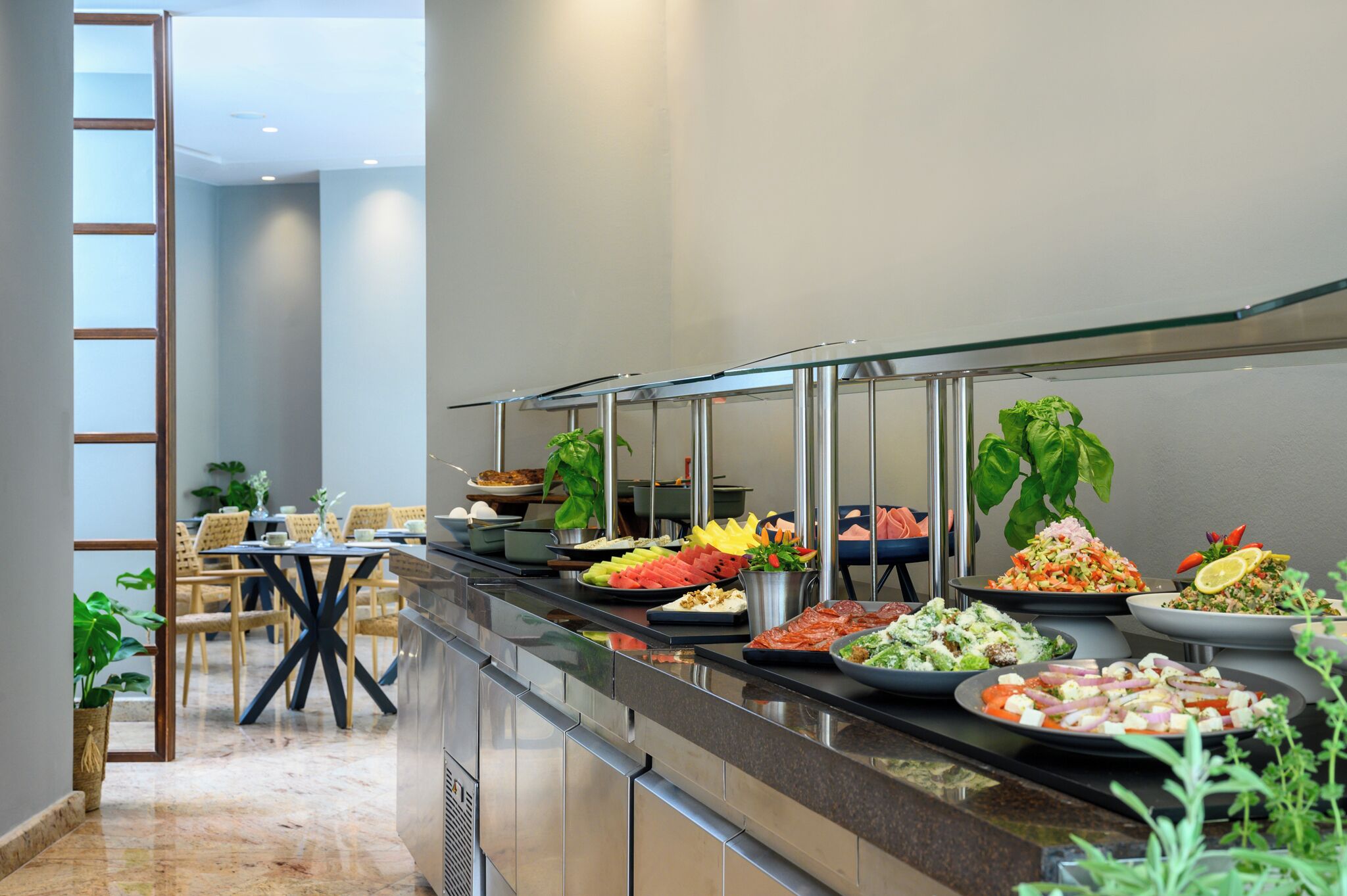 A buffet area with various food options, a seating area with chairs, and a staircase leading to an upper level.