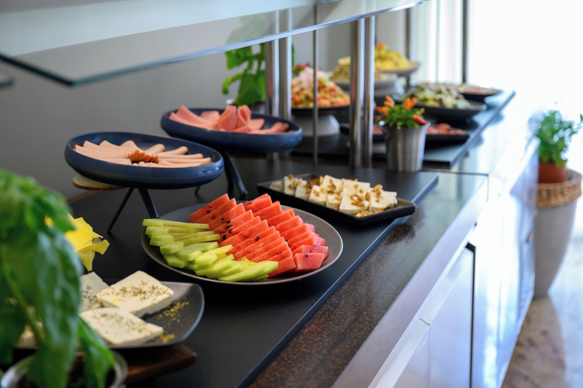 Un buffet proposant une variété de plats, notamment des tranches de pastèque, du fromage et d’autres mets.