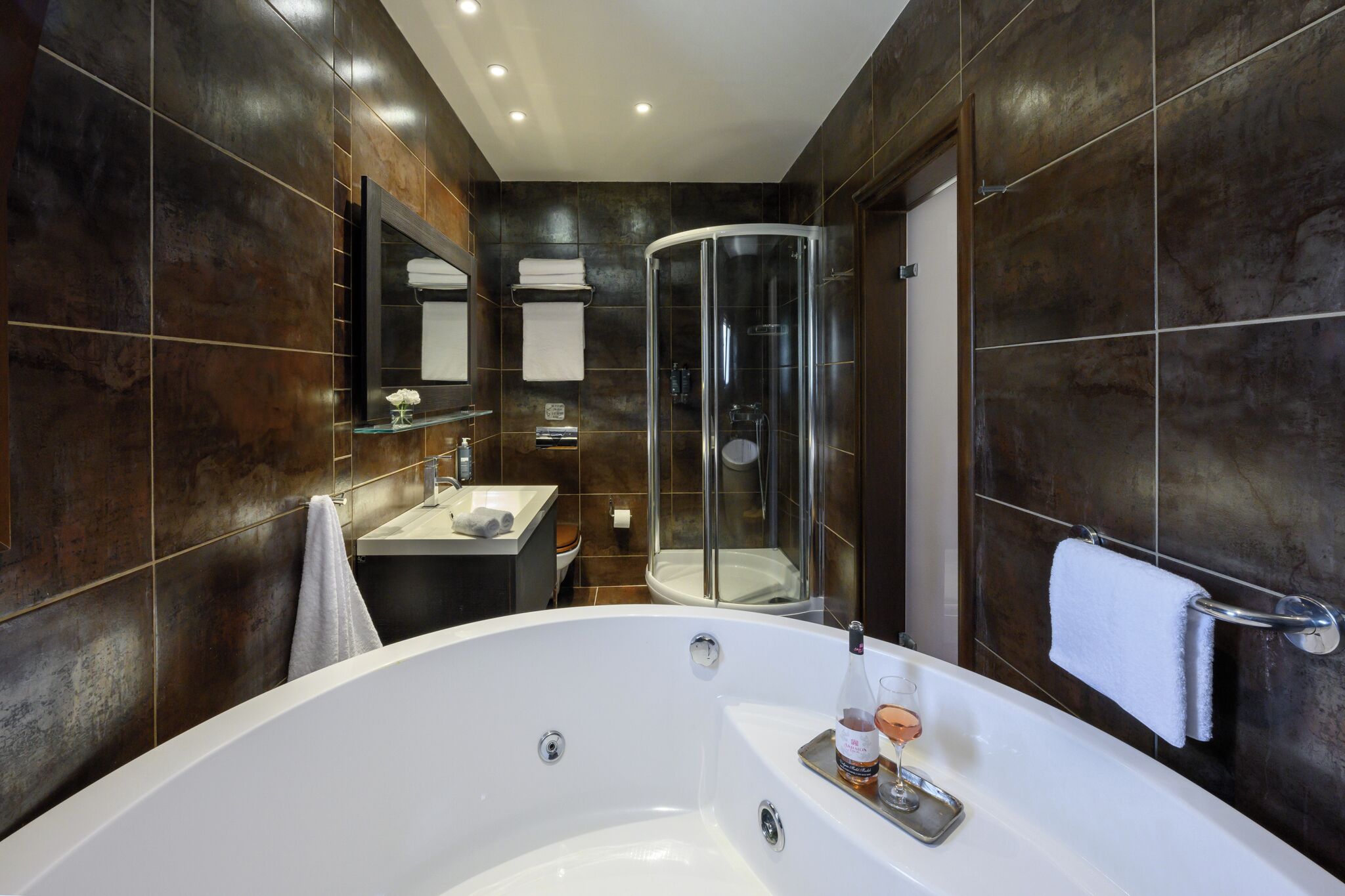 A modern bathroom with a large bathtub, a glass-enclosed shower, and a vanity with a mirror.