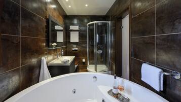 Un baño moderno con una bañera grande, una ducha con cerramiento de vidrio y un tocador con espejo.