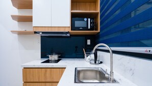 A compact kitchen with a microwave, stove, and sink. - Mango Home & Apartment (Da Nang)