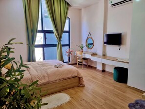 A bedroom with a bed, a desk, a chair, a TV, and a window with curtains. - Mango Home & Apartment (Da Nang)