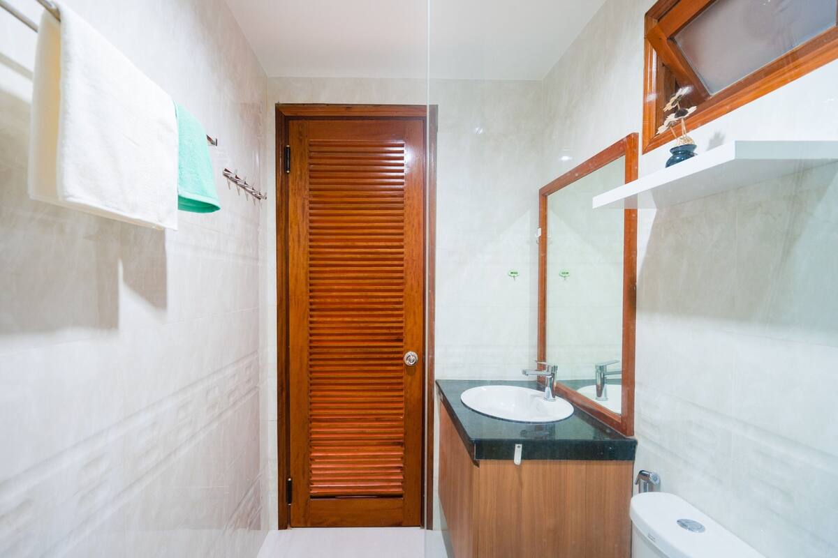 Une salle de bain avec une porte en bois, un lavabo et un miroir.