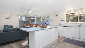 Una cocina moderna con armarios blancos, encimera gris y un comedor con sillas de madera y una mesa.