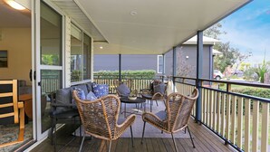 A covered balcony with wicker furniture, a sofa, and a table.