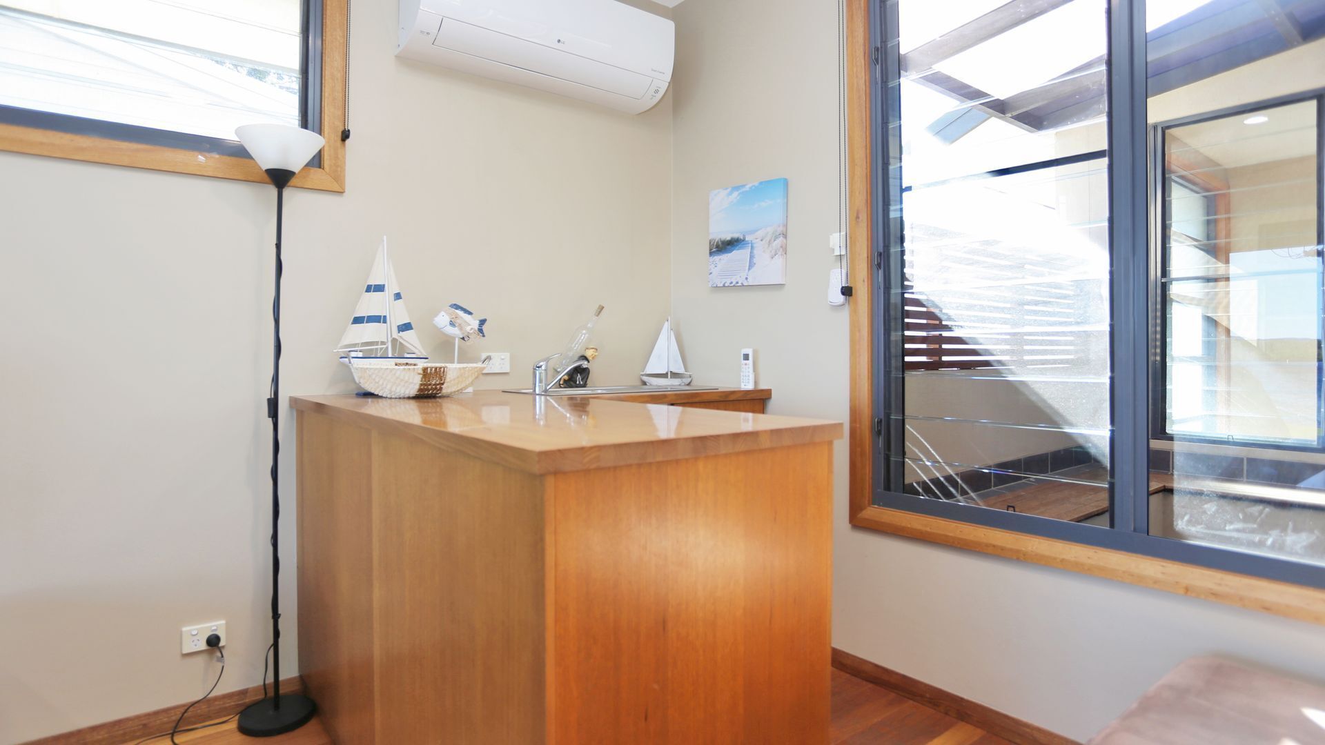 A modern kitchen with a wooden countertop, a sink, and a window with a view of a balcony.