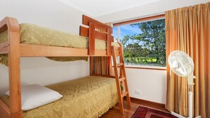 A bunk bed room with a ladder, a window with curtains, and a standing fan. - Stroll To Bennett's Beach (Hawks Nest)