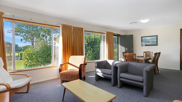 A spacious room with large windows, a dining area, and a seating arrangement. - Stroll To Bennett's Beach (Hawks Nest)