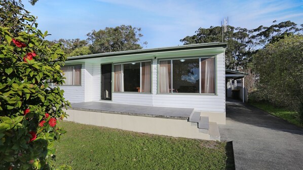 Een gelijkvloers huis met een plat dak, grote ramen en een overdekte veranda.