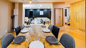 Een eetkamer met een lange tafel gedekt voor een maaltijd, omringd door stoelen.