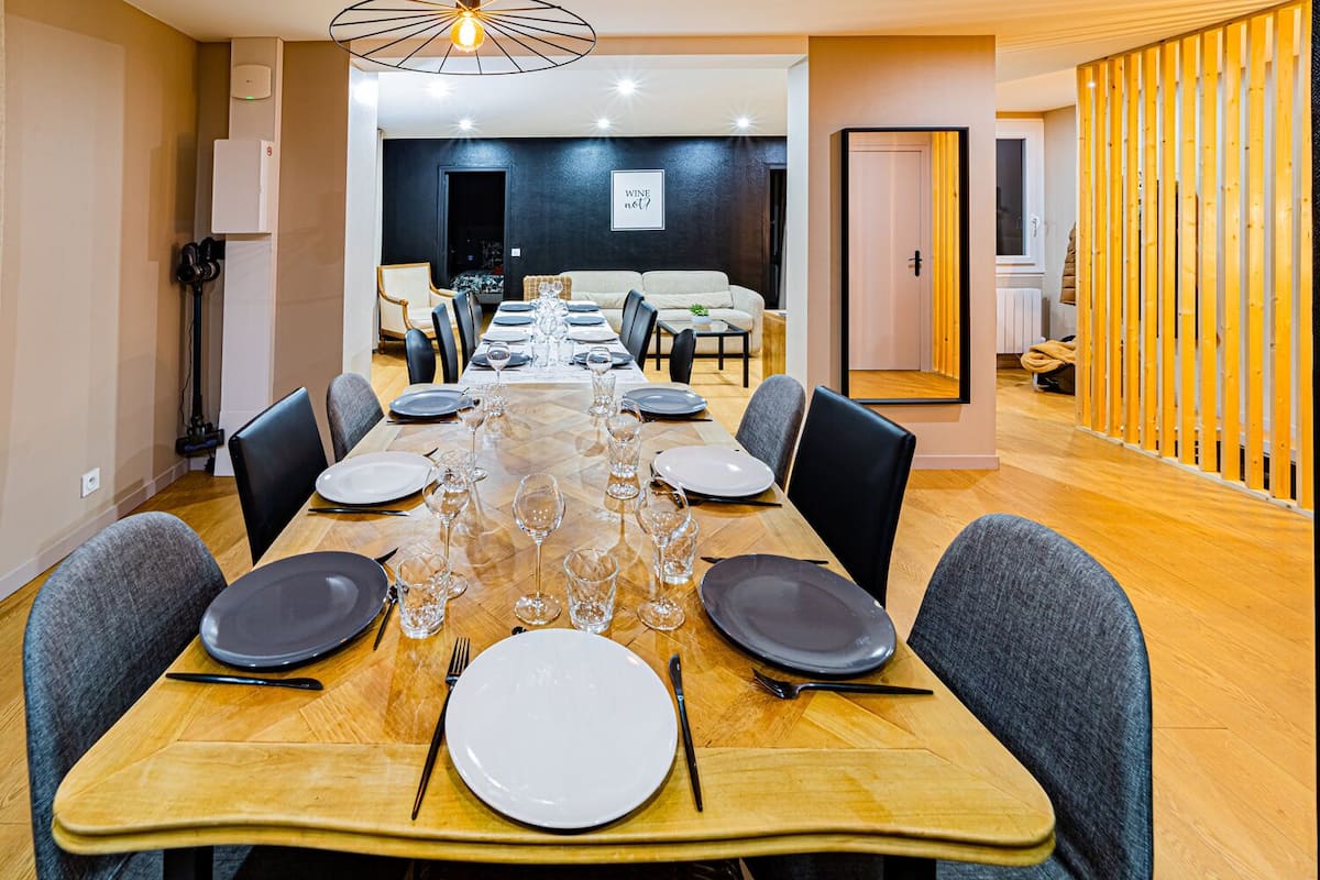 A dining room with a long table set for a meal, surrounded by chairs.