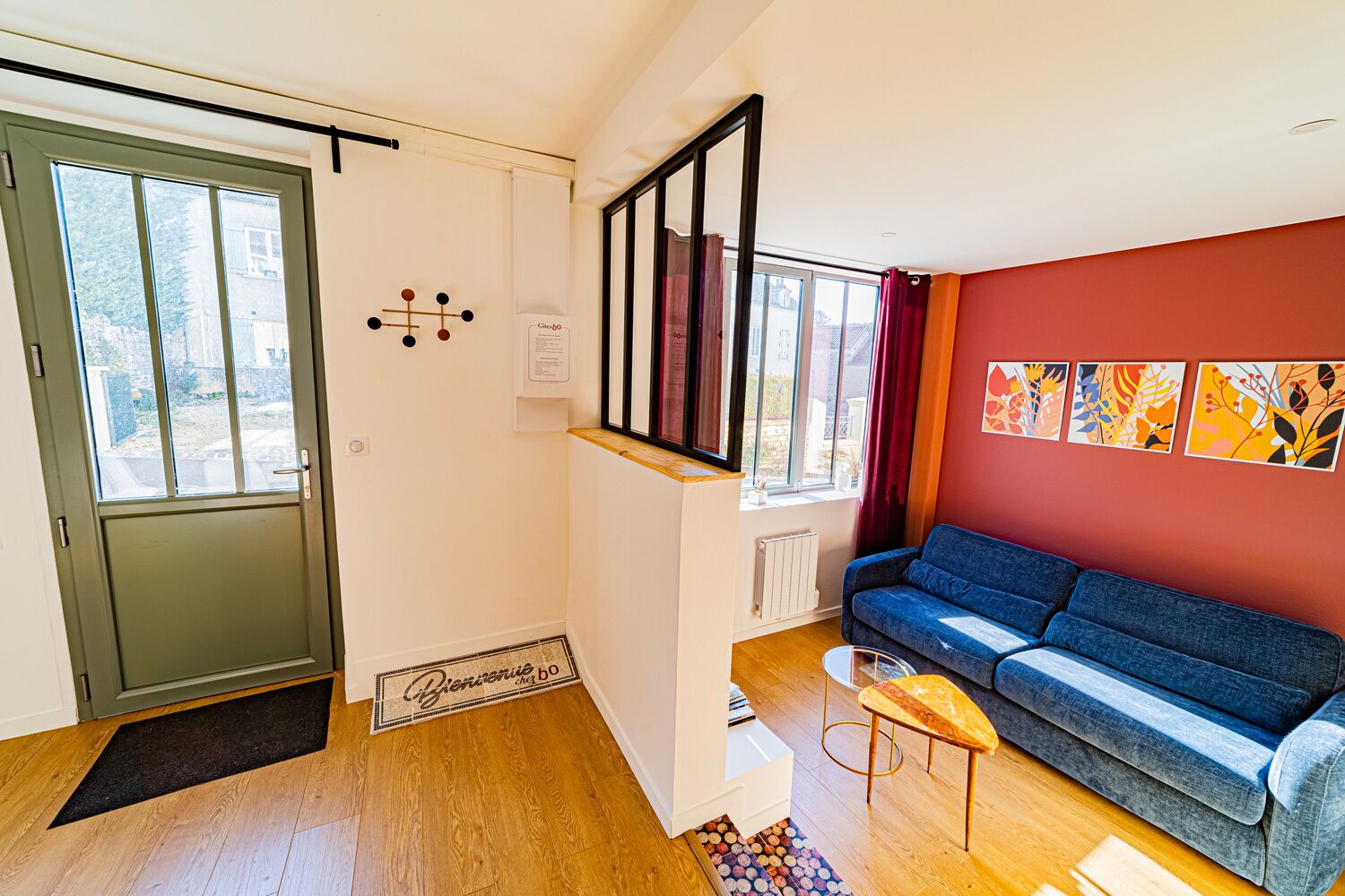 Ein modernes Wohnzimmer mit einem blauen Sofa, Holzboden, einem Heizkörper und einem Fenster mit Vorhängen.