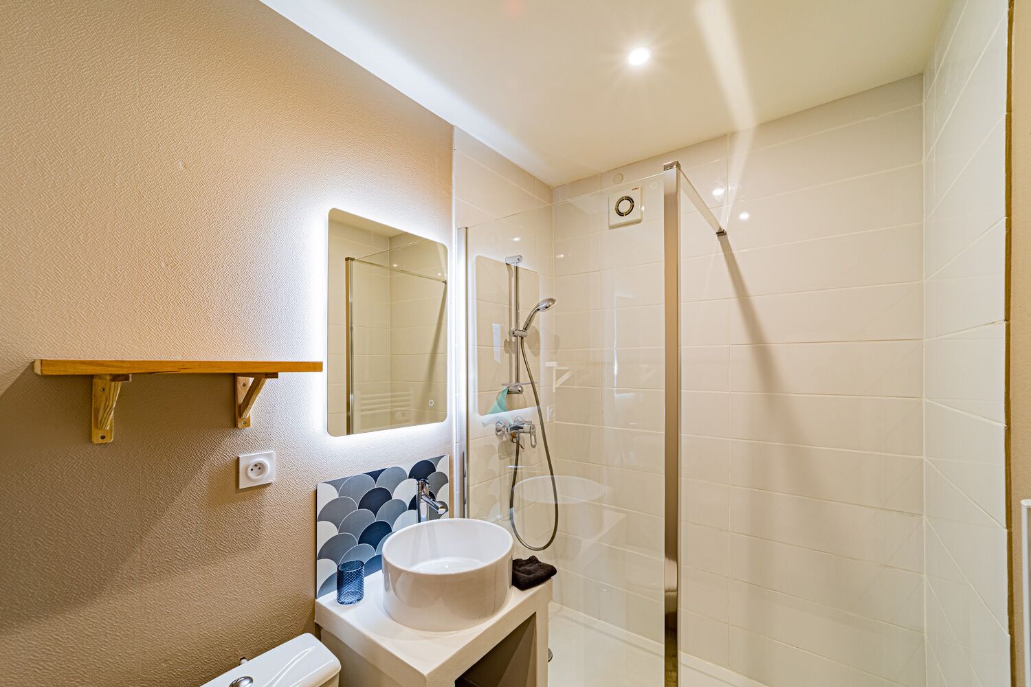 A bathroom with a shower, a sink, a mirror, and a towel rack.