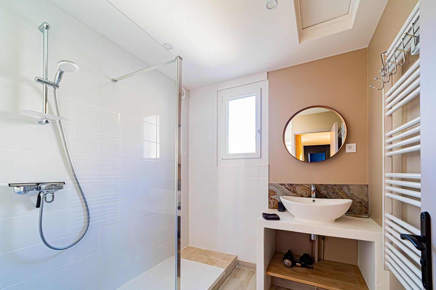 Un baño moderno con ducha de vidrio, un lavabo blanco y un espejo sobre él.
