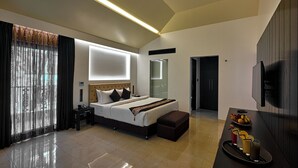 A modern hotel room with a large bed, a bedside table, a flat-screen TV, and a breakfast tray with fruit and juice. - Insignia Hotels & Resorts (Tongi)