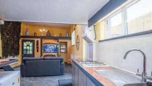 A modern kitchen with a built-in gas stove, a stainless steel sink, and a large window. - Clouds - 1 Bedroom Holiday Home - Milford Haven (Milford Haven)