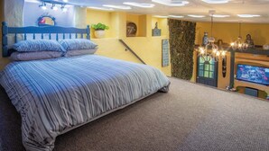 A bedroom with a bed, a desk, a computer, and a wall with a clock and a plant. - Clouds - 1 Bedroom Holiday Home - Milford Haven (Milford Haven)