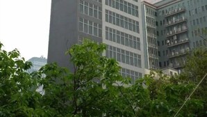 Een hoog, modern gebouw met meerdere verdiepingen en grote ramen.