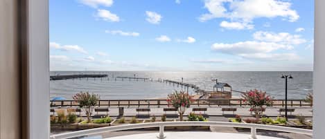 A balcony with a view of the sea, a wooden pier, and a gazebo.