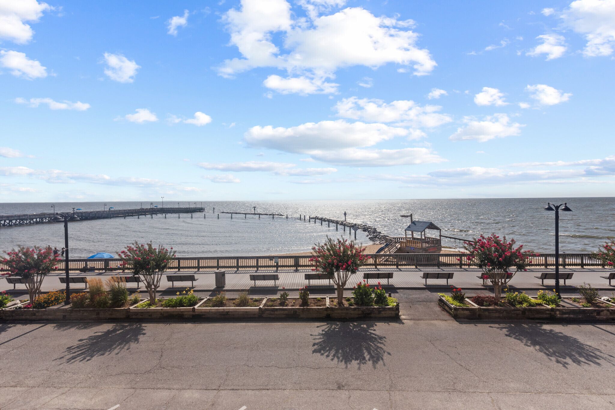 A waterfront promenade with benches, a gazebo, and a pier extending into the water.